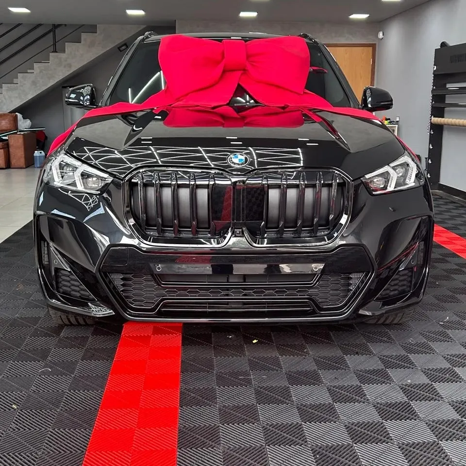 Capô e grade de um SUV preto refletindo a iluminação do estúdio, depois da aplicação de PPF.