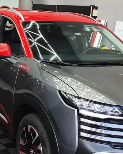 SUV cinza de teto vermelho no box de aplicação da RFilmes, visto da frente.