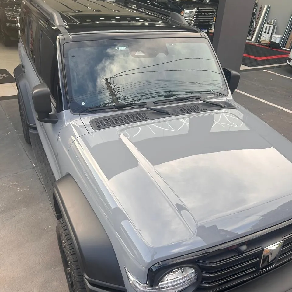 SUV cinza com o teto envelopado em preto brilhante, visto de cima na entrada do estúdio.